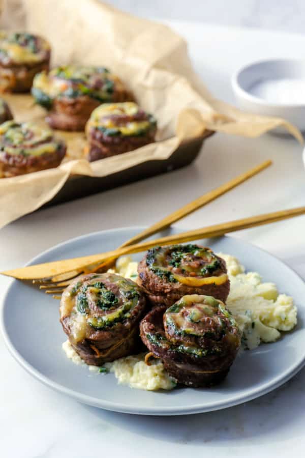 Flank Steak stuffed with spinach and havarti on a plate with gold fork and knife