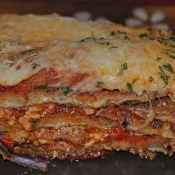 A close up of a slice eggplant parmesan on a plate.
