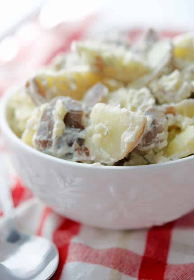 Red Bliss Dill Potato Salad is super creamy and made with red bliss, skin on potatoes, mayonnaise, and fresh dill in a white serving bowl.  