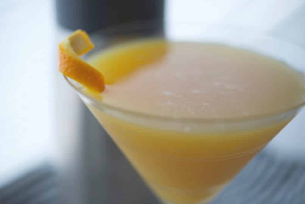 A close up of a glass of orange juice, with Coconut martini