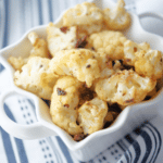 Cauliflower in a white bowl on a blue and white napkin.