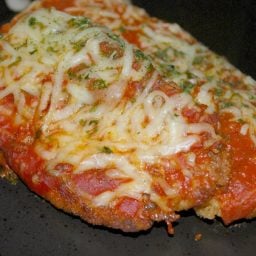 A close up of chicken cutlets with tomato sauce and mozzarella cheese.