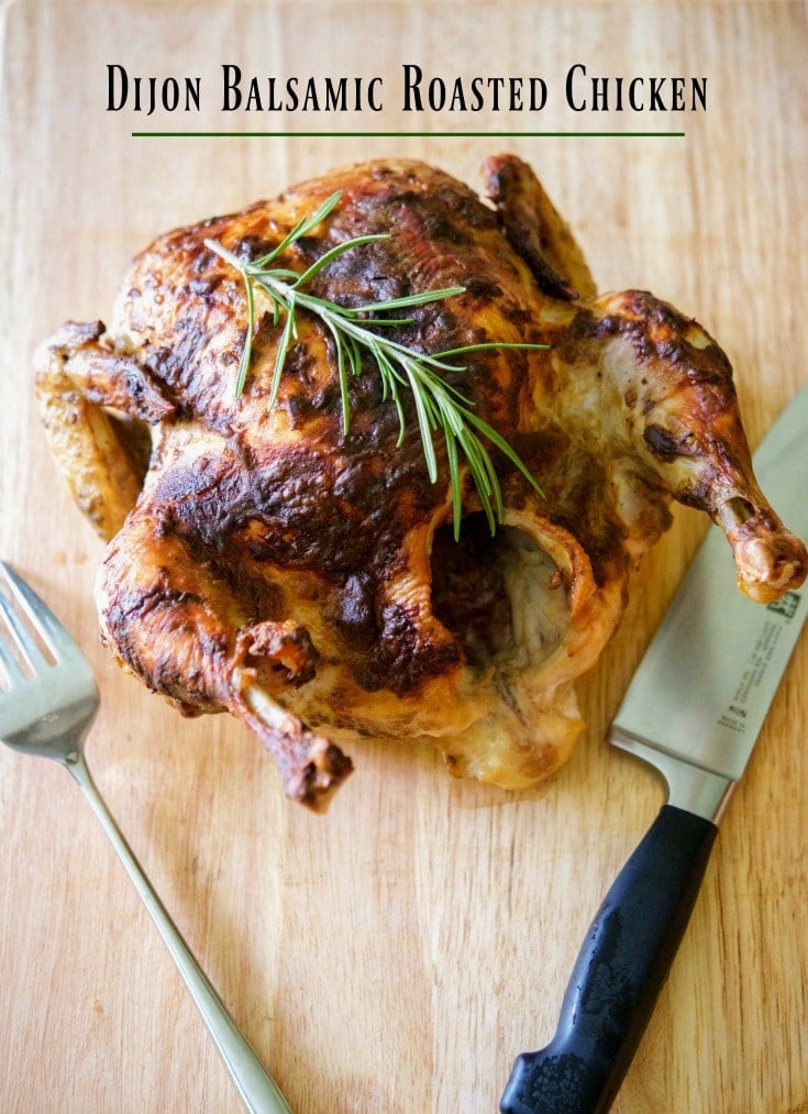 Balsamic Roasted Chicken on a wooden cutting board with a carving knife and fork.