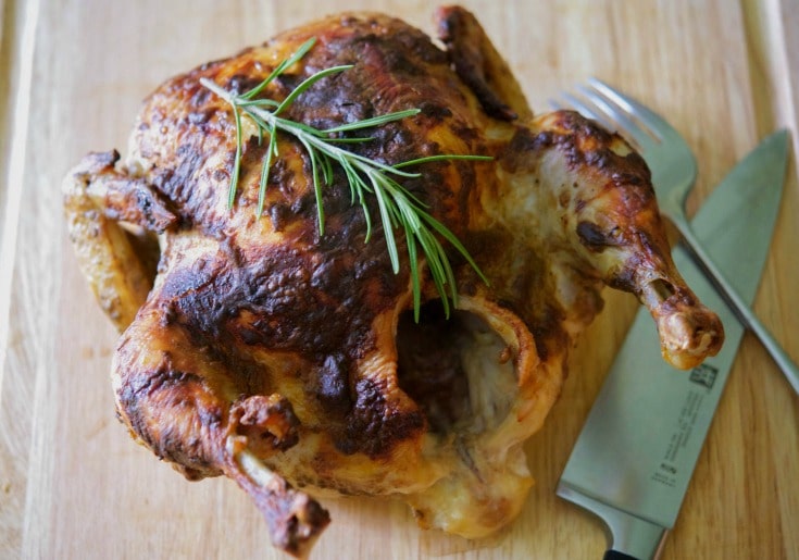 A close up of Balsamic Roasted Chicken on a wooden cutting board.