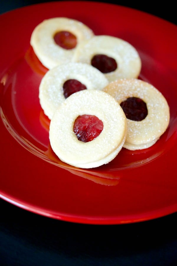 Raspberry Linzer Tarts are one of our favorite holiday treats and are made with two buttery cookies filled with tart raspberry preserves. 