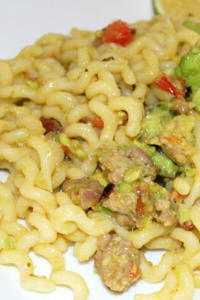 a close up of curly pasta with sausage and avocado