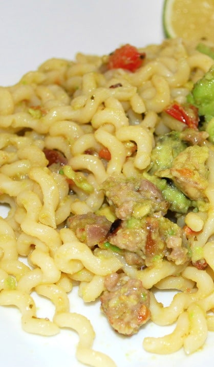 a close up of curly pasta with sausage and avocado