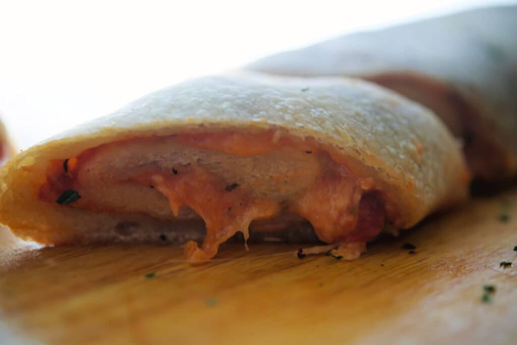 A close up of pizza roll stromboli on a wooden cutting board
