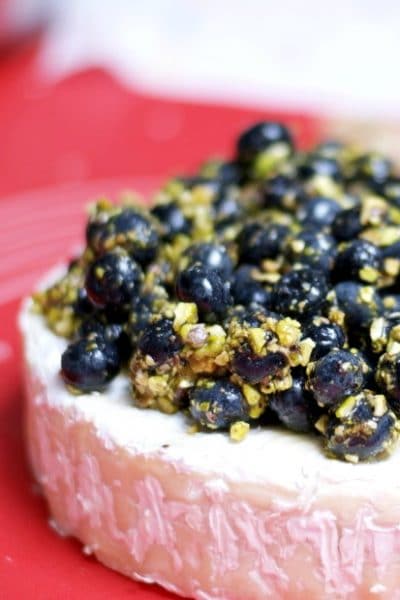 A close up of blueberries and pistachios on top of Brie cheese.