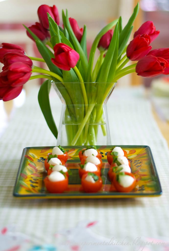A vase filled with tulips on a table and Caprese Cherry Tomatoes