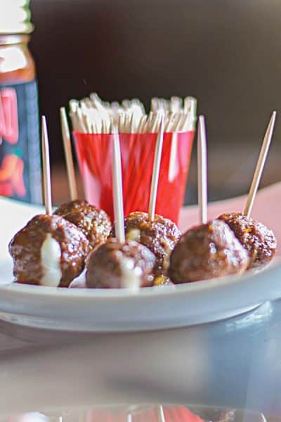 Cheese stuffed mini meatballs on a plate with toothpicks.