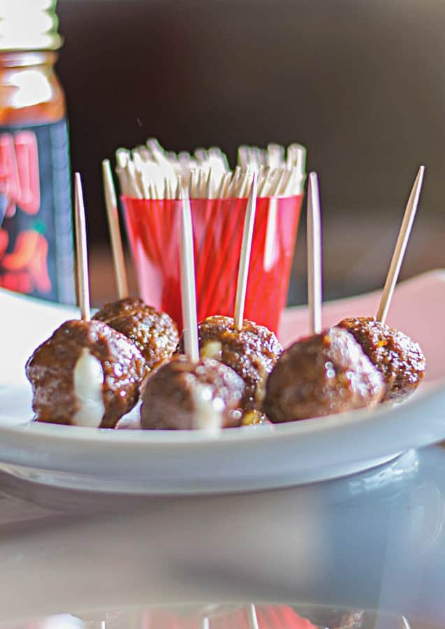 Cheese stuffed mini meatballs on a plate with toothpicks. 