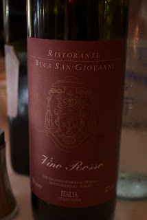 A close up of a bottle and a glass of wine, with Red