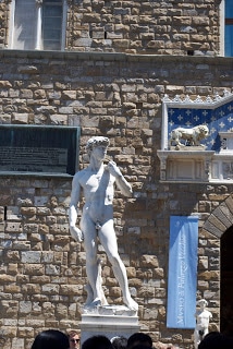 A large stone statue of David in front of a brick building