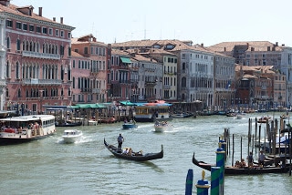 A small boat in a body of water with Grand Canal in the background