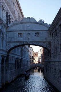 A large bridge over some water with Bridge of Sighs in the background