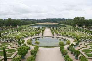 A close up of a garden with Palace of Versailles in the background