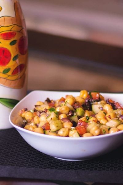 Mediterranean Chick Pea Salad made with capers, Kalamata olives, cucumbers, tomatoes and fresh basil in a balsamic vinaigrette. 