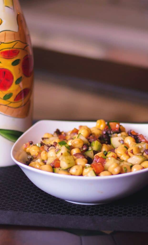 Mediterranean Chick Pea Salad made with capers, Kalamata olives, cucumbers, tomatoes and fresh basil in a balsamic vinaigrette. 