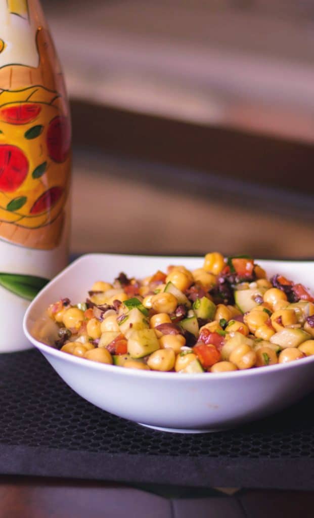 Mediterranean Chick Pea Salad made with capers, Kalamata olives, cucumbers, tomatoes and fresh basil in a balsamic vinaigrette. 