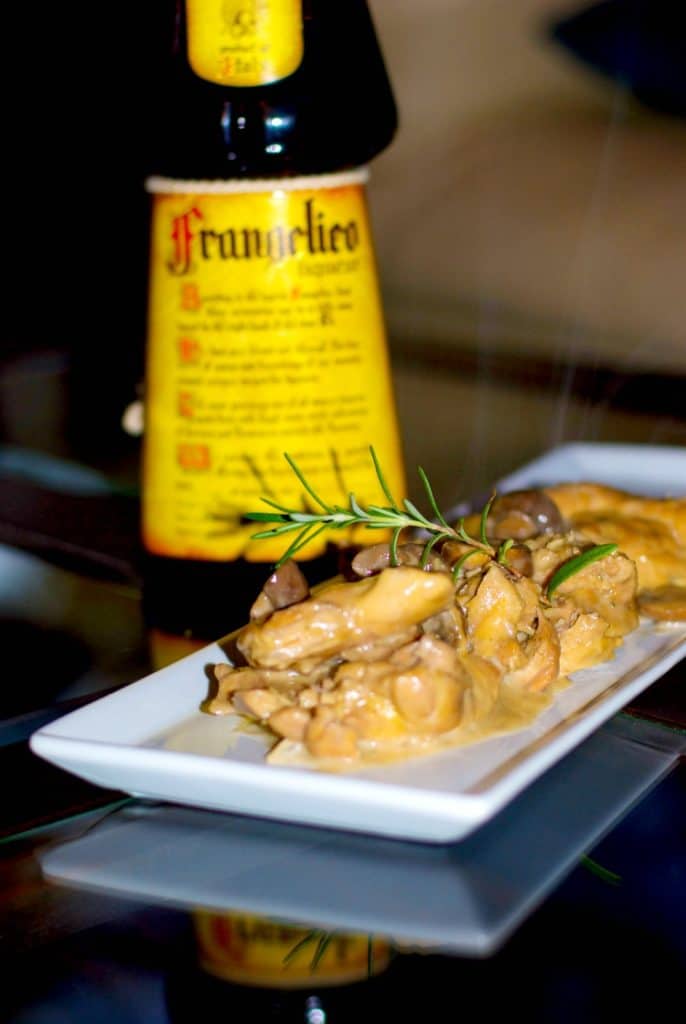 A plate of food and a bottle of wine on a table, with Sauce and Chicken