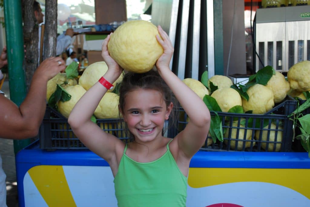 A girl holding an Italian lemon over her head