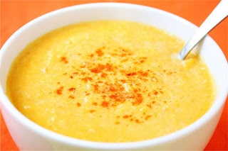 A bowl of soup and a spoon, with Bisque and Seafood