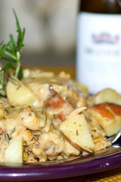 A close up of Chicken in a white wine rosemary sauce with red potatoes.