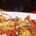 Chicken thighs braised in a Dutch oven with champagne, grape tomatoes, capers and red potatoes make a tasty one pot meal.
