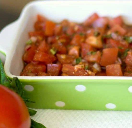 A close up of bruschetta in a green and white dish.