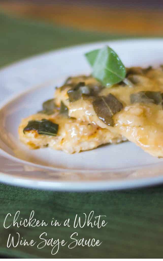  A close up of boneless chicken breasts in a white wine sage sauce on a plate. 