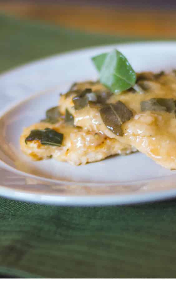 Boneless chicken breasts in a white wine sage sauce on a plate.