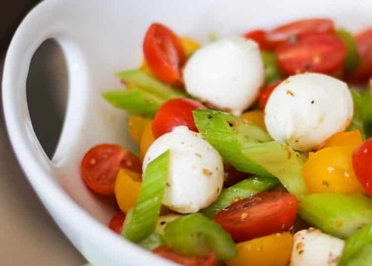 A bowl of food on a plate, with Salad and Mozzarella