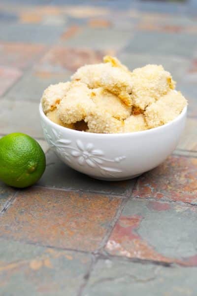 A bowl chicken nuggets on a slate table with a lime.