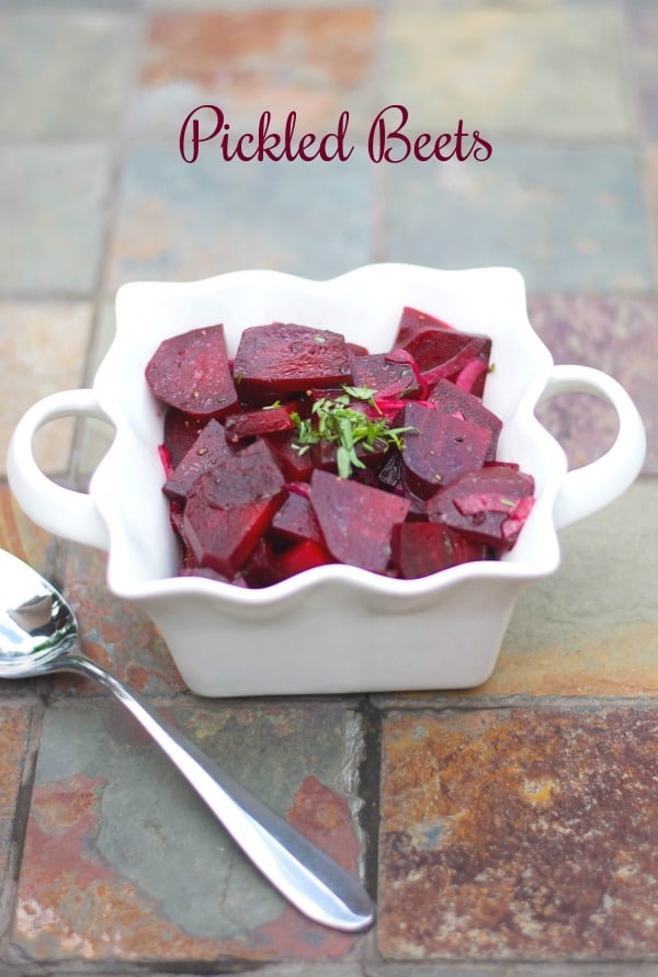 Pickled beets in a square white bowl.