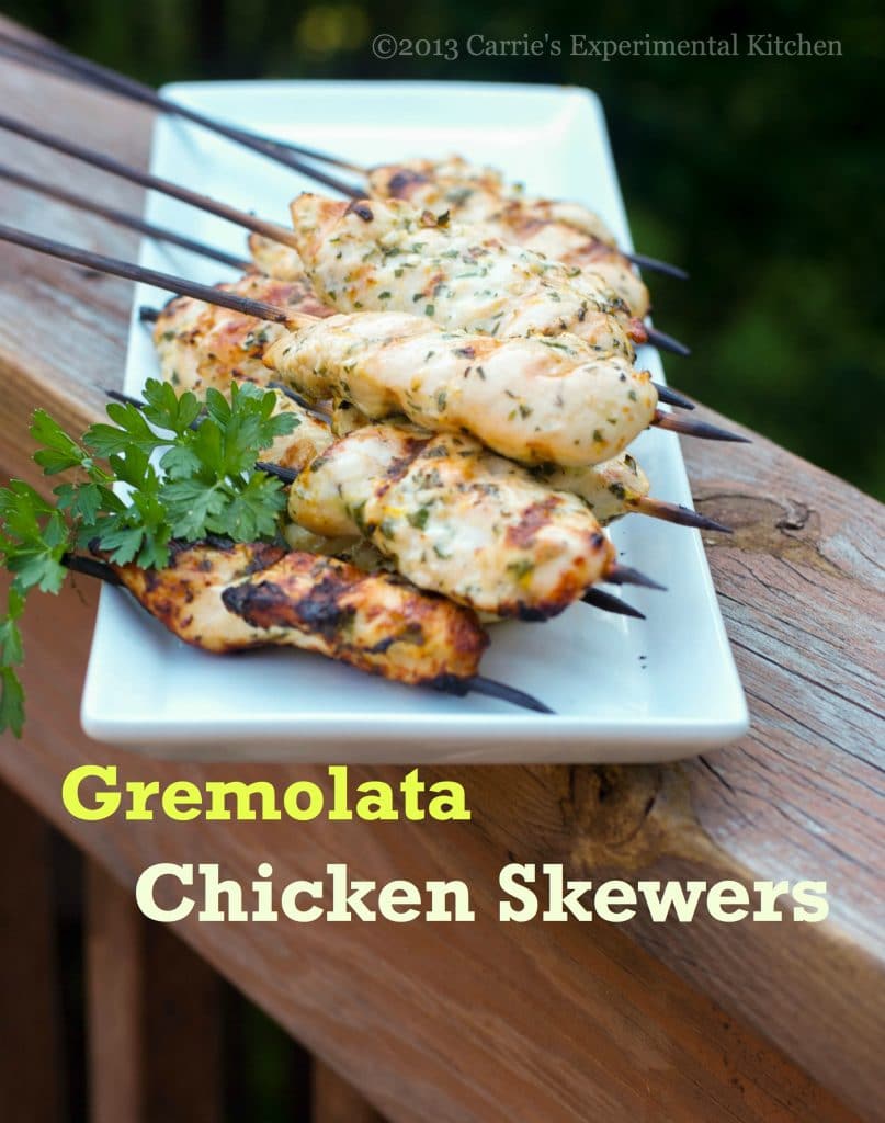 A plate of food on a wooden table, with Chicken and Skewer