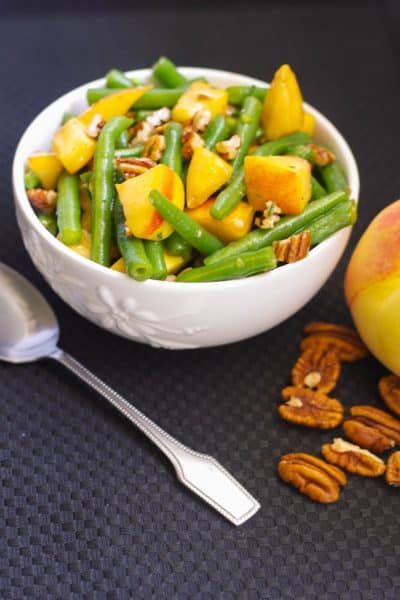 Fresh green beans and sliced peaches tossed with chopped pecans in a maple vinagrette is a delightfully flavorful Autumnal salad.