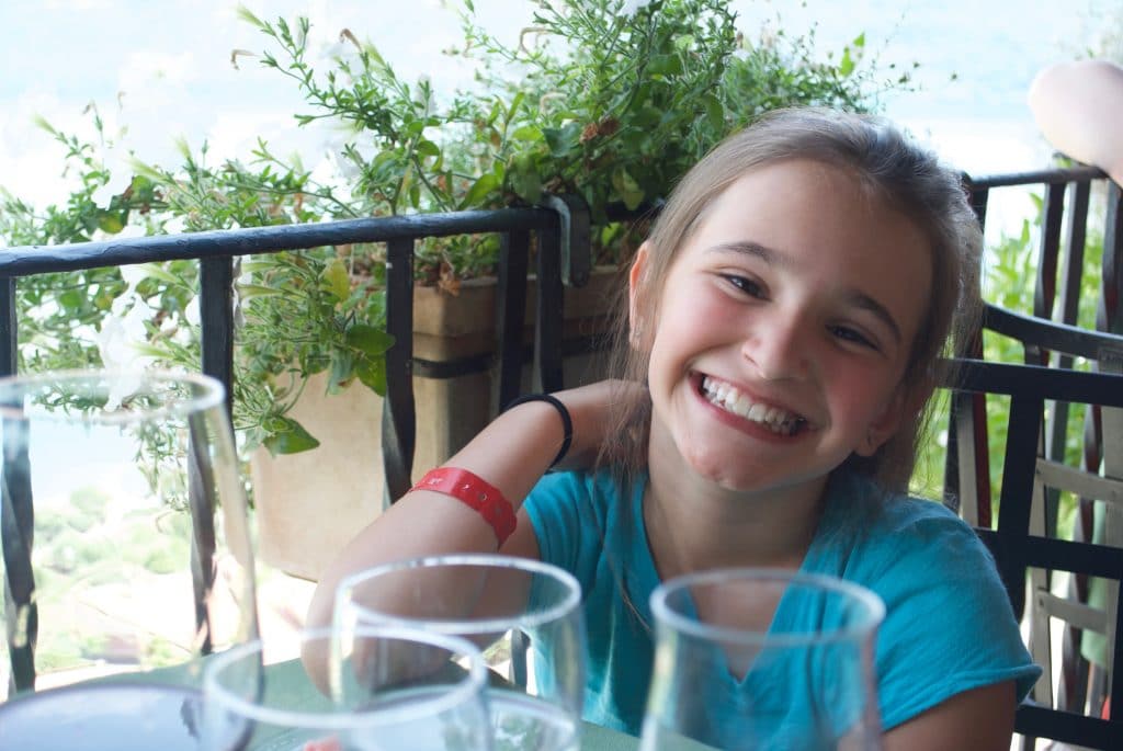 A girl sitting at a table outside in Italy