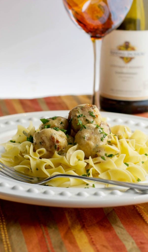 A closeup of a plate of turkey swedish meatballs over egg noodles. 