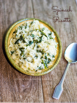 Spinach risotto in a dish with a spoon on a wooden table. 