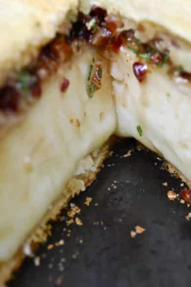 A close up of a baked brie with cherries.