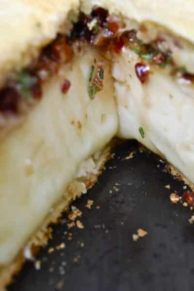 A close up of a baked brie with cherries.