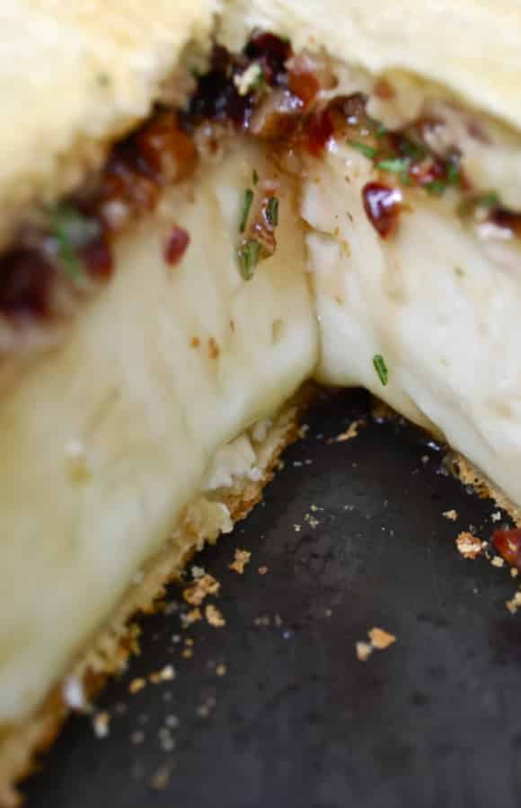 A close up of a baked brie with cherries.