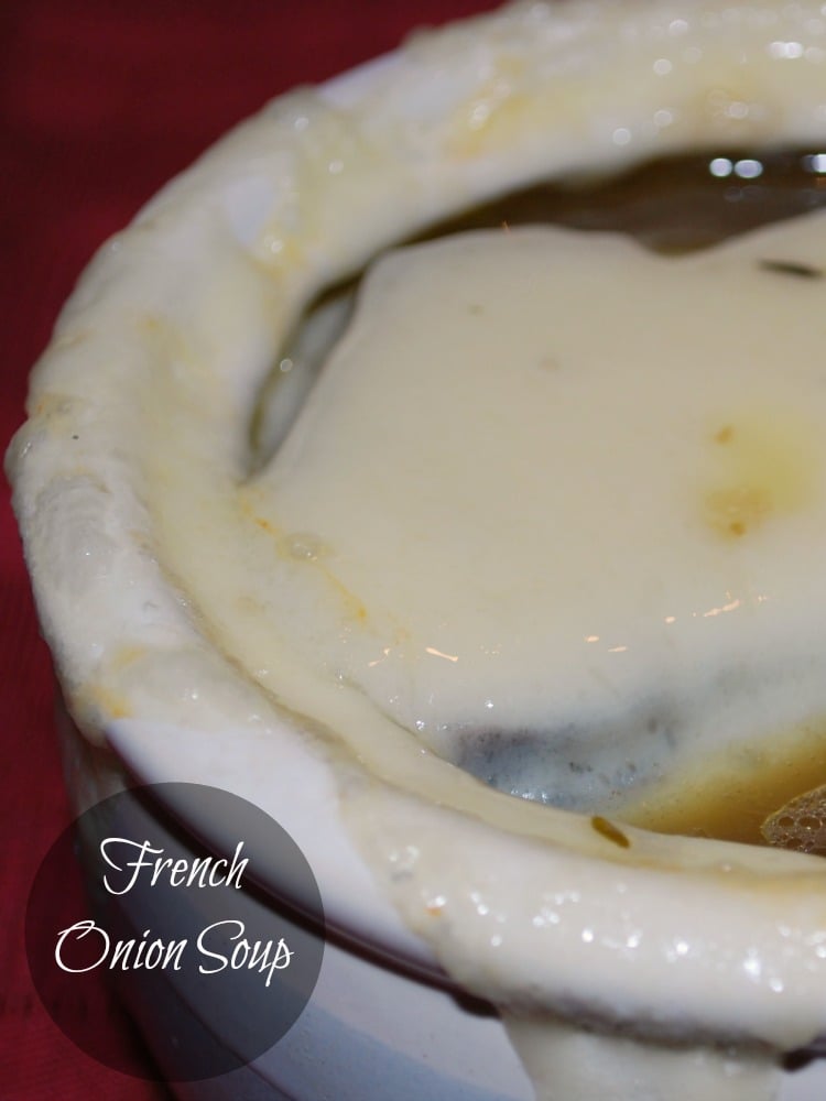 A close up of french onion soup in a soup bowl with melted cheese. 