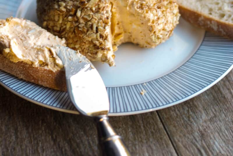 Pumpkin Maple Cheese ball made with cream cheese, pumpkin puree, maple syrup, and fresh thyme, topped with chopped pecans.
