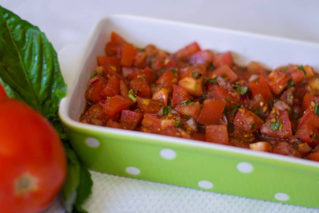 A green and white dish with bruschetta. 