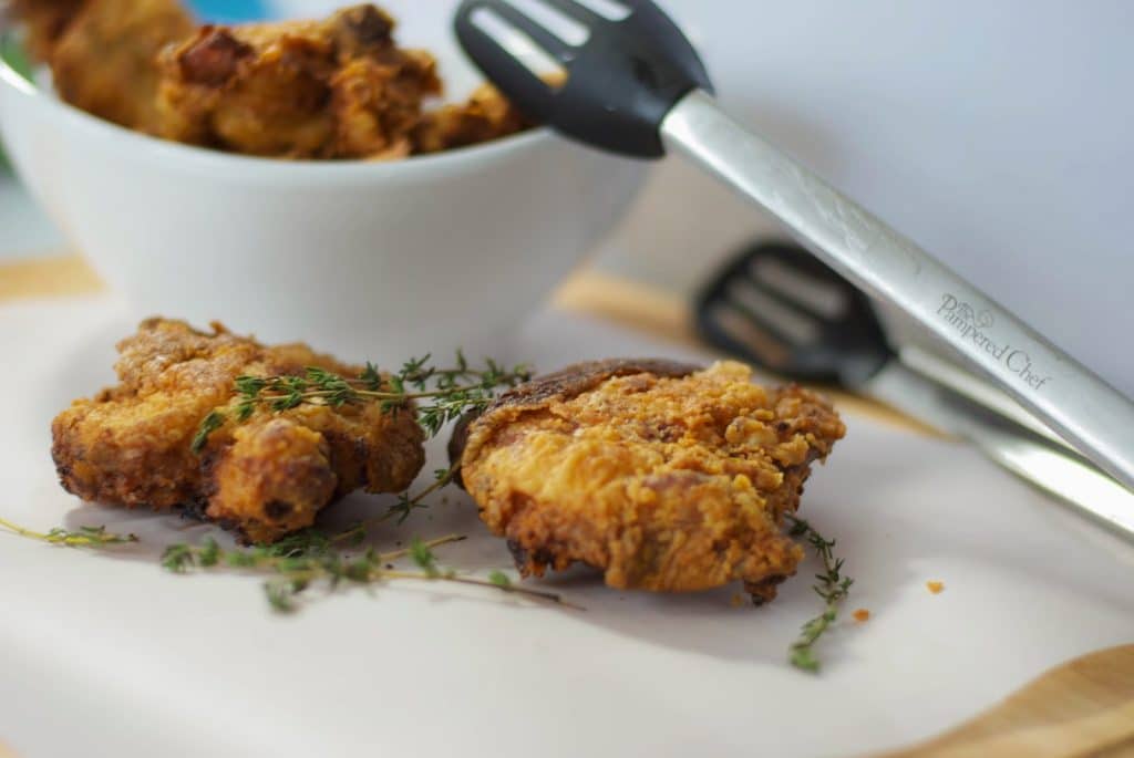 Buttermilk Fried Chicken on a table with tongs. 