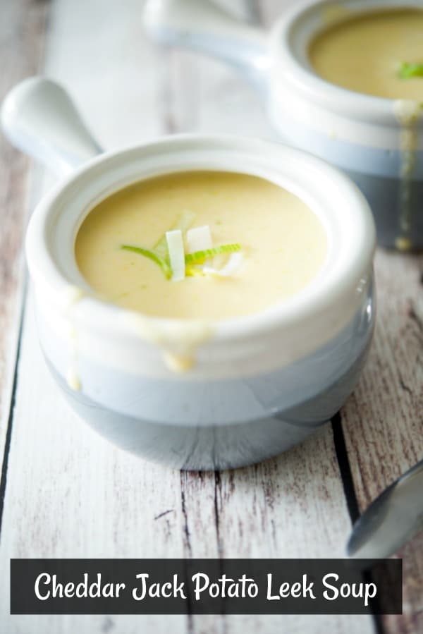 Close up of Cheddar Jack Potato Leek Soup in a soup crock on a wooden table. 