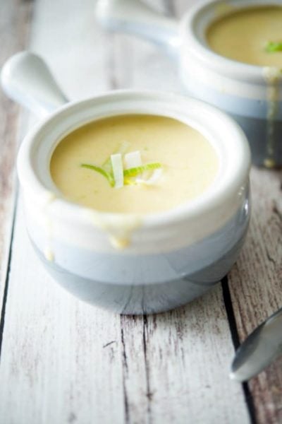 Cheddar Jack Potato Leek Soup in a soup crock on a wooden table.