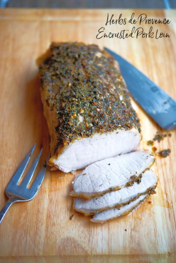 Herbs de Provence Encrusted Pork Loin on a wooden cutting board. 